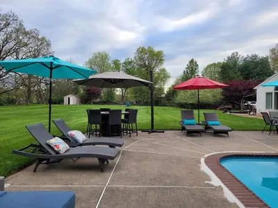 a patio with chairs and umbrellas next to a pool at Bridle Pool House in Lansdale