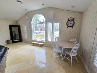 a dining room with a table and chairs and a clock at Bridle Pool House in Lansdale
