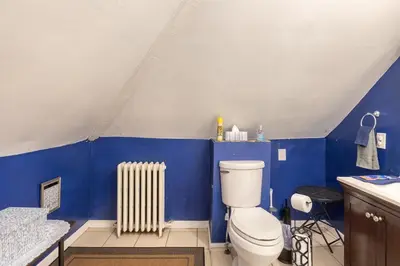 a blue bathroom with a toilet and a radiator at Quaint 3rd Floor Loft in Highland Park