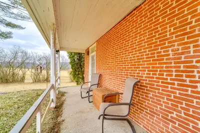 a porch with two chairs and a table and a brick wall at 3 Mi to Penns Creek Access Hideaway with Grill! in Millmont