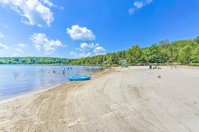 a beach with a blue boat in the water at Family Home in Arrowhead Lake with Fire Pit! in Pocono Lake