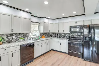 a kitchen with white cabinets and stainless steel appliances at Fire Pit and Game Room Spacious Poconos Retreat! in Long Pond