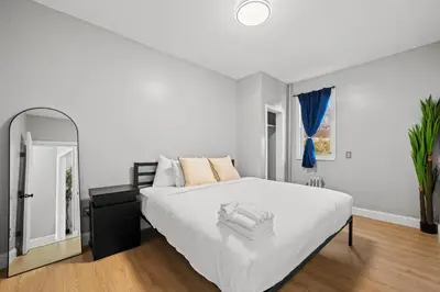 a white bedroom with a large bed and a mirror at Spacious Stay Near EWR And NYC Mins to Train in Bayonne