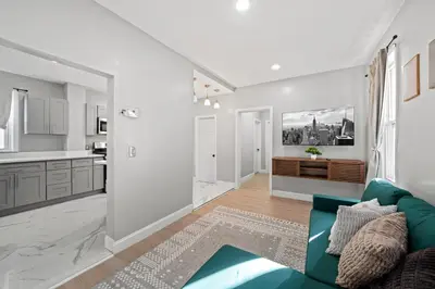 a living room with a green couch and a kitchen at Spacious Stay Near EWR And NYC Mins to Train in Bayonne