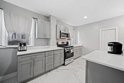 a kitchen with white cabinets and a stove top oven at Spacious Stay Near EWR And NYC Mins to Train in Bayonne