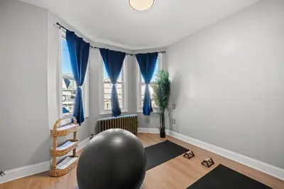 a living room with a large window with blue drapes at The City Spacious Stay Near EWR And NYC Mins to Train in Bayonne
