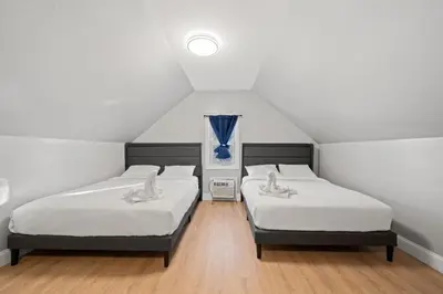 two beds in a attic room with a window at The City Spacious Stay Near EWR And NYC Mins to Train in Bayonne