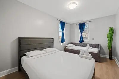 a bedroom with two beds and a window with blue curtains at The City Spacious Stay Near EWR And NYC Mins to Train in Bayonne