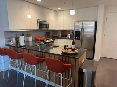 a kitchen with a counter with chairs and a refrigerator at NEWLuxe 2bd2ba w Pool & More in Hoboken