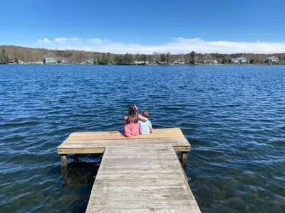 two children sitting on a dock on a lake at Newton Lake in Malinchak Airport