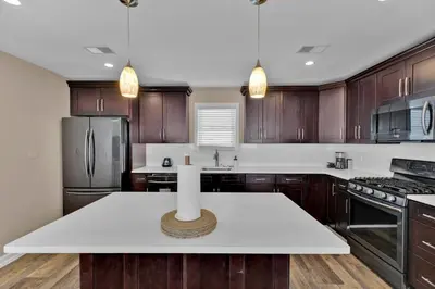a kitchen with wooden cabinets and a white counter top at The Seabreeze Haven- Luxury 3BR Coastal Retreat - Near Beach & Free Parking in Keansburg