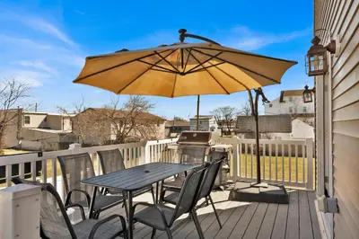 a table and chairs with an umbrella on a deck at The Seabreeze Haven- Luxury 3BR Coastal Retreat - Near Beach & Free Parking in Keansburg