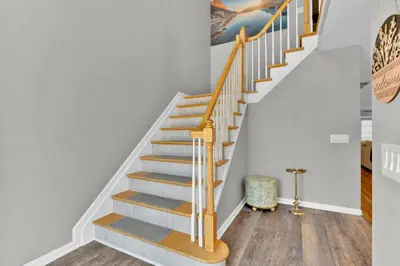 a staircase with white walls and wooden treads at The Seabreeze Haven- Luxury 3BR Coastal Retreat - Near Beach & Free Parking in Keansburg