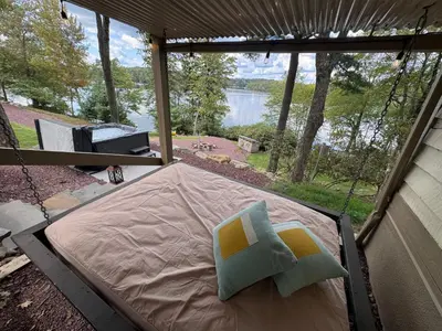 a bed in a screened in porch with a view of a lake at Lakefront Cabin with Hot Tub, Views & Fireplace in Lake Harmony