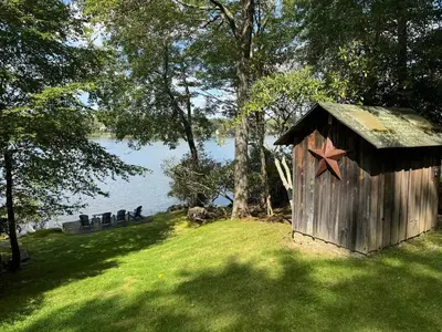 a wooden out house with a star on it in the grass at Lakefront Cabin with Hot Tub, Views & Fireplace in Lake Harmony