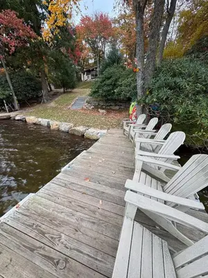 a row of white chairs sitting on a wooden bridge at Lakefront Cabin with Hot Tub, Views & Fireplace in Lake Harmony