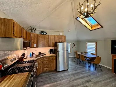 a kitchen with a stainless steel refrigerator and a table at Lake View Cottage - Private Dock and Fire Pit in Lake Harmony