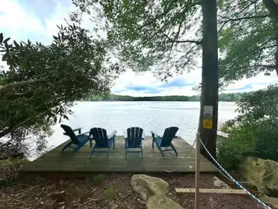 four chairs sitting on a dock next to a lake at Lake View Cottage - Private Dock and Fire Pit in Lake Harmony