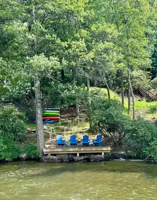 a group of chairs sitting on a dock next to a river at Lake View Cottage - Private Dock and Fire Pit in Lake Harmony