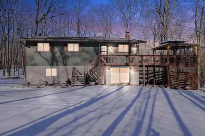 a house with a deck in the snow at 4 Br Cozy Cabin Sleeps 8 Pool Table Arcade Beach in Gouldsboro