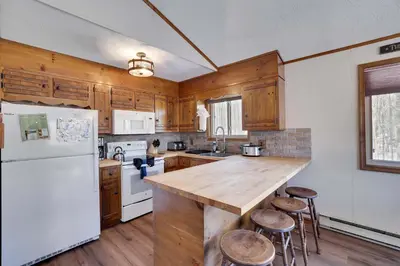 a kitchen with a white refrigerator and wooden cabinets at 4 Br Cozy Cabin Sleeps 8 Pool Table Arcade Beach in Gouldsboro