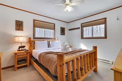 a bedroom with a large bed and two windows at 4 Br Cozy Cabin Sleeps 8 Pool Table Arcade Beach in Gouldsboro