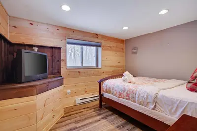a bedroom with a bed and a flat screen tv at 4 Br Cozy Cabin Sleeps 8 Pool Table Arcade Beach in Gouldsboro