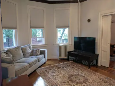 a living room with a couch and a flat screen tv at Comfortable 2 Bedroom House with Big Yard 30 Minutes to New York City in Ridgefield Park