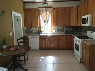 a kitchen with wooden cabinets and a table and a window at Comfortable 2 Bedroom House with Big Yard 30 Minutes to New York City in Ridgefield Park
