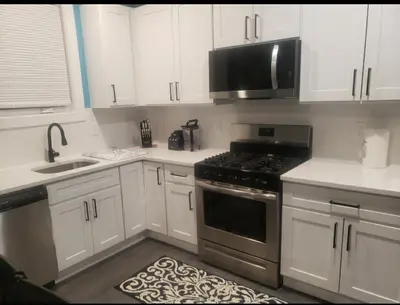 a kitchen with white cabinets and a stove top oven at Comfy 3 bedroom house in Newark