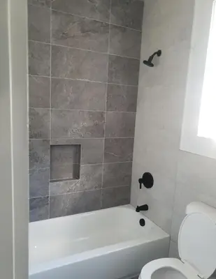 a bathroom with a white tub and a toilet at Comfy 3 bedroom house in Newark