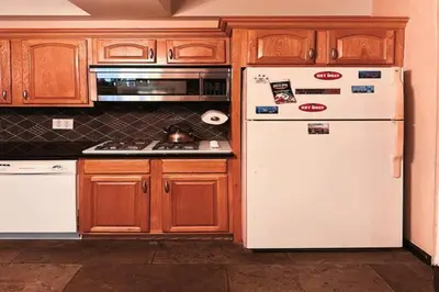 a kitchen with a white refrigerator and wooden cabinets at NY - NJ Tennis Suites - Sleeps 40 - 15 Mins to NYC in Union City
