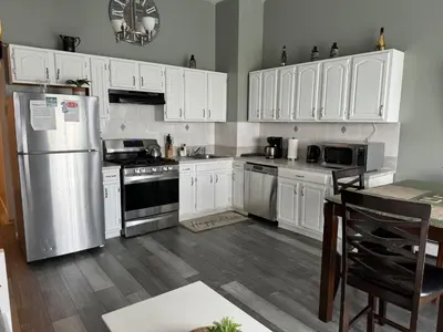 a kitchen with white cabinets and a stainless steel refrigerator at Triple See NY Now - Sleeps 41 -15 Mins to NYC in Union City
