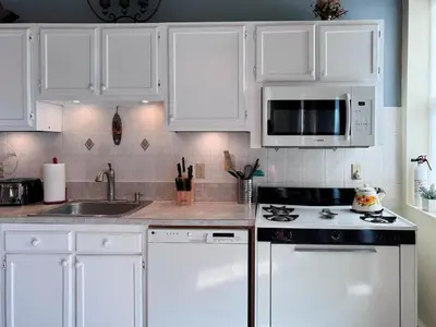 a kitchen with white cabinets and a stove and microwave at Mega Stunning Skyline View - APT 4-5 Combination - 6 Bedroom - Sleeps 25 - 15 mins to NYC in Union City