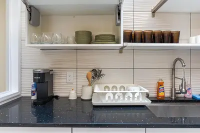 a kitchen counter with a dish drying rack next to a sink at Spacious 3BR Oasis with Patio & Arcade Fun in Philly in Philadelphia