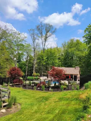a fence in front of a yard with a house at Glamorous Cottage Rental with Outdoor Lounge and Pool on 40 Acres in Pine Bush, New York in Pine Bush