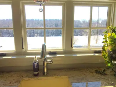 a kitchen with a faucet in front of three windows at Stylish Cottage Loft Rental on a Farm in Lancaster County near Philadelphia, Pennsylvania in Christiana