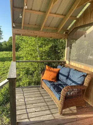 a wicker couch sitting on a wooden deck at Gorgeous Finger Lakes Accommodation near Ithaca for Glamping in New York in Brooktondale