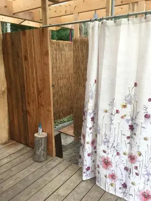 a patio with a white curtain with flowers on it at Gorgeous Finger Lakes Accommodation near Ithaca for Glamping in New York in Brooktondale