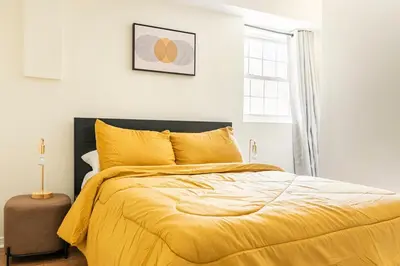 a bedroom with a bed with yellow sheets and a window at 2BR Stay for Crews & Families in Elizabeth