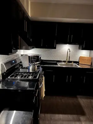a kitchen with black cabinets and a stove and a sink at 2BR Stay for Crews & Families in Elizabeth
