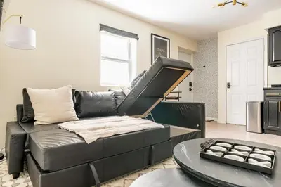a living room with a black leather couch and a table at 2BR Stay for Crews & Families in Elizabeth