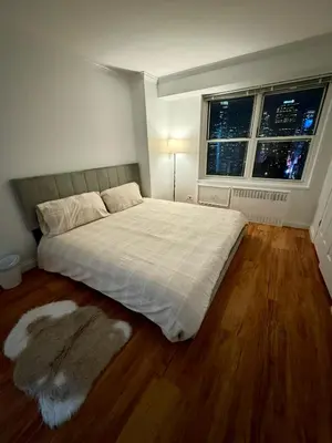 a bedroom with a large bed and two windows at Midtown High Floor Fantastic Panoramic City View Corner 2 Bedroom Apartment in New York