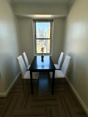 a dining room with a table and chairs and a window at Midtown High Floor Fantastic Panoramic City View Corner 2 Bedroom Apartment in New York