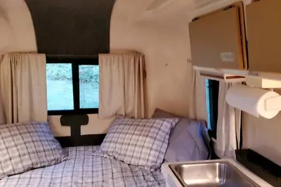 a small bedroom with a bed and a sink at Unique Caravan for Vintage Glamping Experience in Pine Bush, New York in Pine Bush
