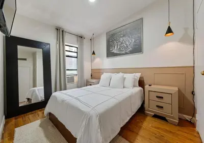 a bedroom with a white bed and a mirror at Three Bedroom Rental in Midtown West , June to Aug 90 days stay required in New York