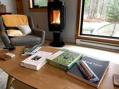 a table with books and a fireplace in a living room at Gorgeous Cottage for Two, Overlooking Pond on 20 acres, Glamping in Pennsylvania in Spring Mills