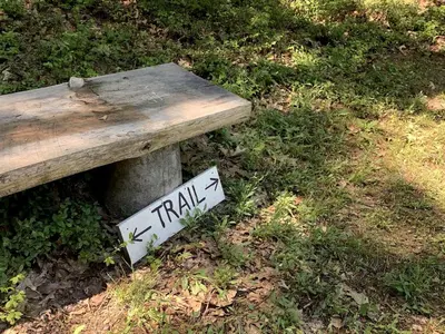 a wooden bench with a trail sign next to it at Gorgeous Cottage for Two, Overlooking Pond on 20 acres, Glamping in Pennsylvania in Spring Mills