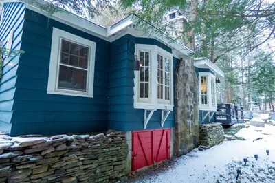 a blue house with a red door and a stone wall at Enchanted Fox Dell Cottage in Monticello