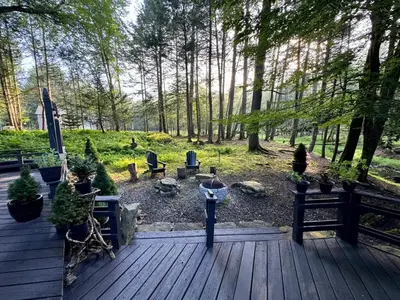 a wooden deck with potted plants and trees at Enchanted Fox Dell Cottage in Monticello